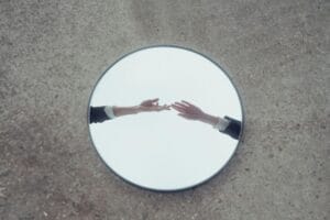 Les mains se tendent pour se connecter à un miroir sur le sol.